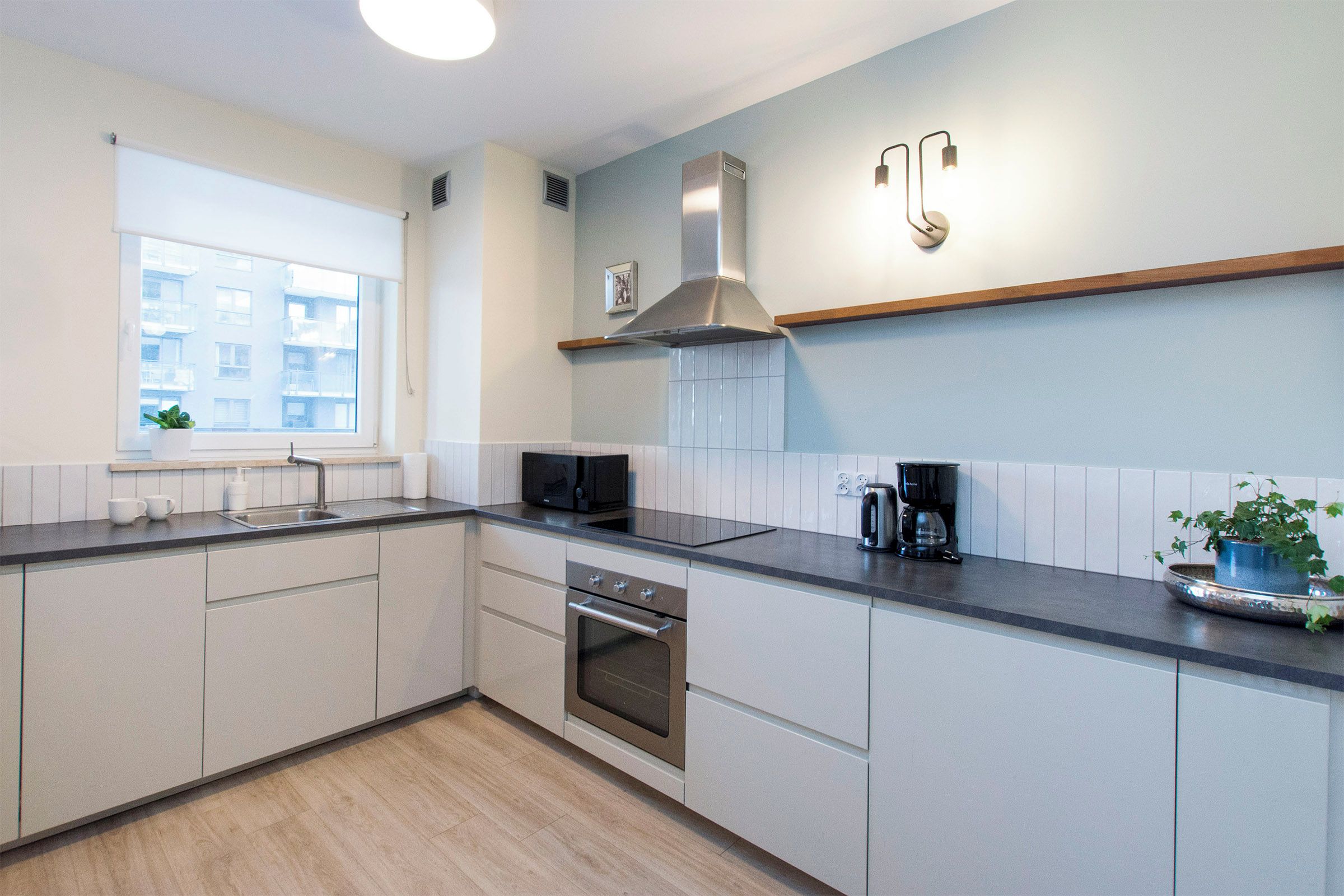 Een moderne keuken met een inbouwoven, magnetron en een roestvrijstalen afzuigkap.