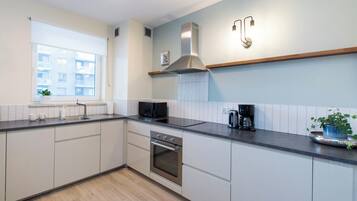 Een moderne keuken met een inbouwoven, magnetron en een roestvrijstalen afzuigkap.