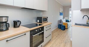 A modern kitchen with a microwave, coffee maker, and oven. - Shipyard Apartments by Apartmore (Gdańsk)