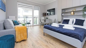 Ett modernt hotellrum med en säng, en soffa, ett litet bord och en balkong med utsikt.