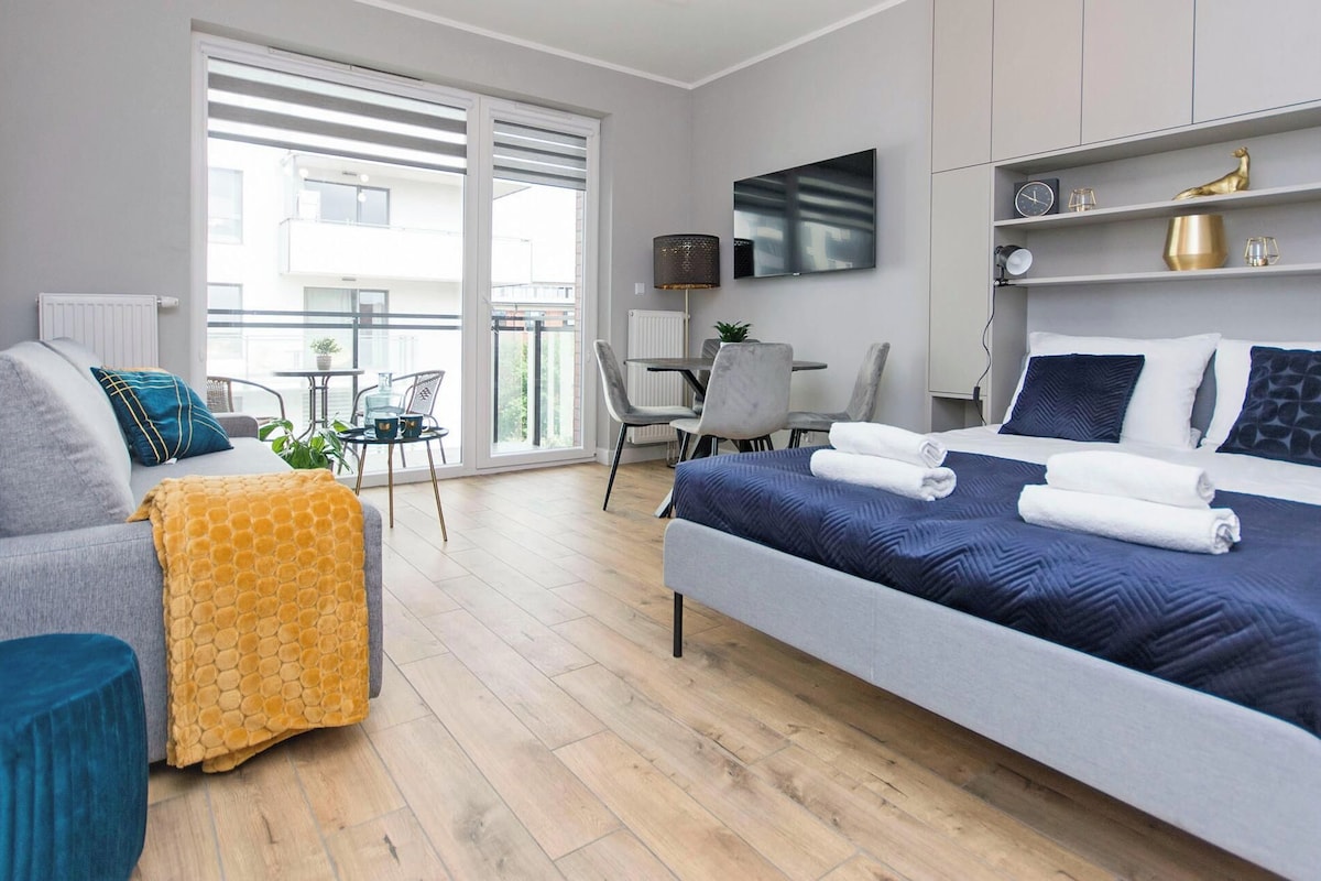 Ein modernes Hotelzimmer mit Bett, einer Sitzecke, einem kleinen Tisch und einem Balkon mit Blick.