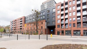 En byggnad med flera våningar, där fasaden består av en blandning av tegel och moderna material, ett övergångsställe och en klar himmel.