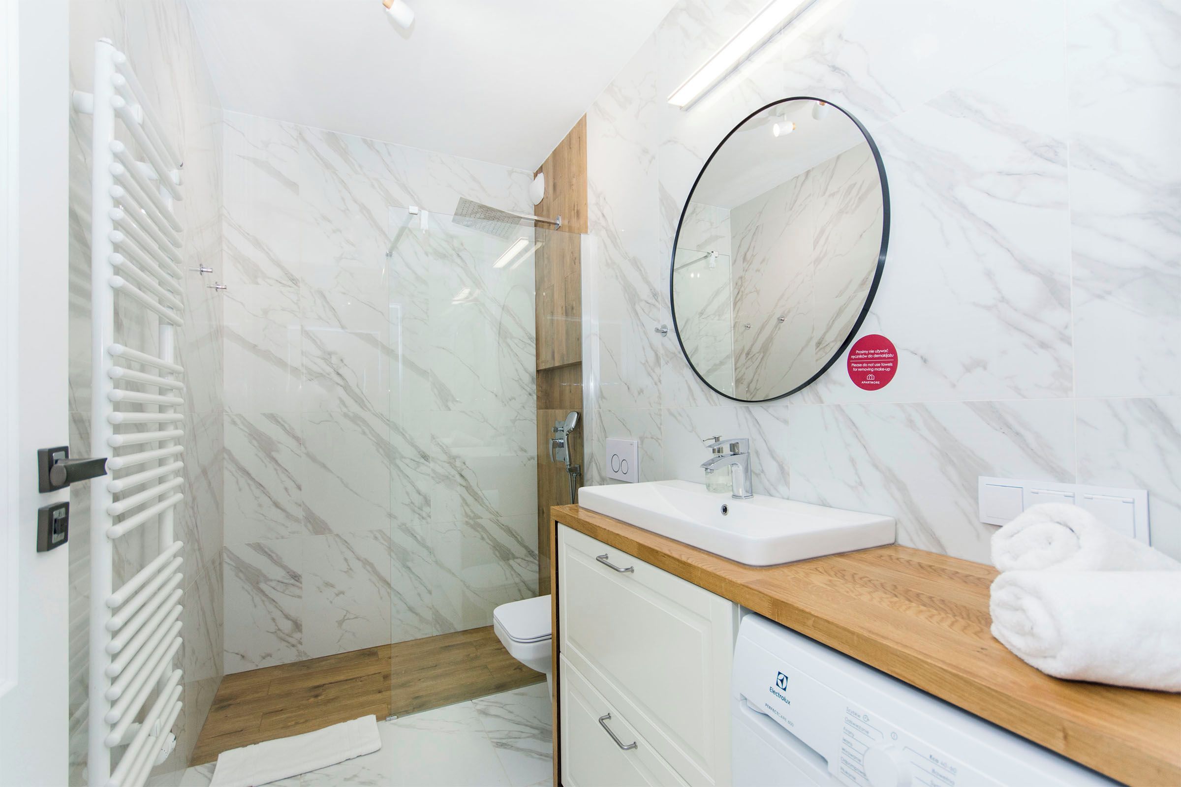 A modern bathroom with a glass shower enclosure, a white sink, and a wooden vanity.