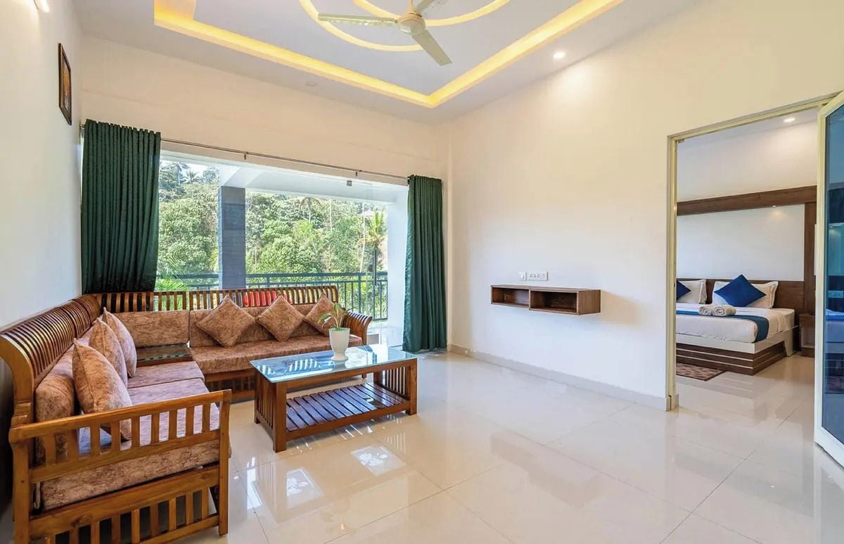 A modern living room with a sofa set, a coffee table, and a bed with a view.