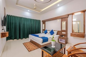 Una habitación de hotel con cama, televisión, escritorio, silla y espejo.