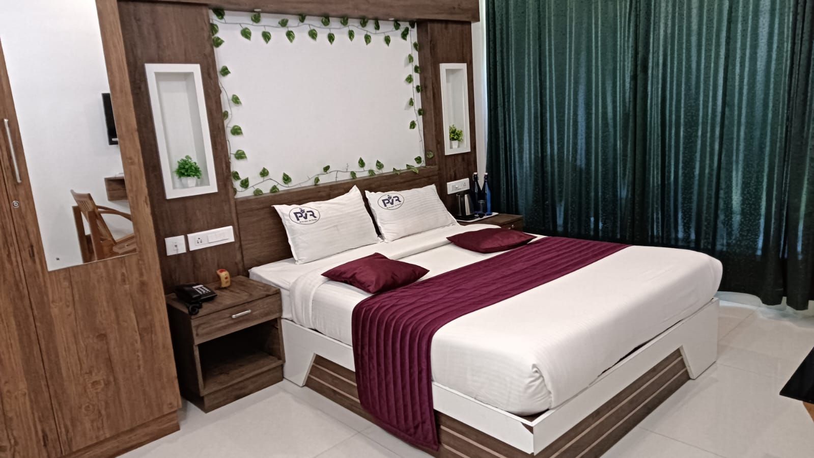 A hotel room with a bed, nightstands, a mirror, and a curtain.