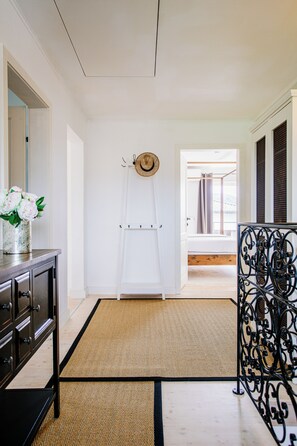 A hallway with a white door, a black metal gate, and a wooden floor.