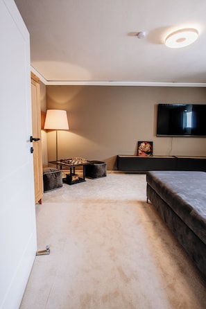 A bedroom with a bed, a TV mounted on the wall, a lamp, and a chessboard on a table.
