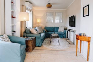 A modern living room with a sectional sofa, a coffee table, and a TV mounted on the wall.