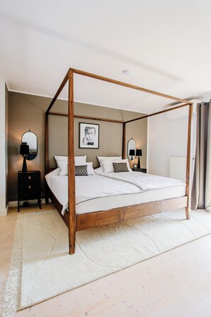 A four-poster bed with a wooden frame, white bedding, and a white rug on a wooden floor. - Stylish Country Cottage near Salzburg (Nußdorf am Haunsberg)