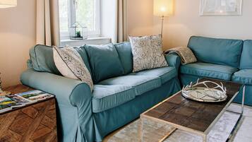 Ein modernes Wohnzimmer mit einer Eckcouch, einem Couchtisch und einem Fenster mit Vorhängen.
