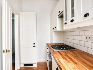 A kitchen with white cabinets, a wooden countertop, and a gas stove. - Stylish Victorian Flat near Finsbury Park (Greater London)