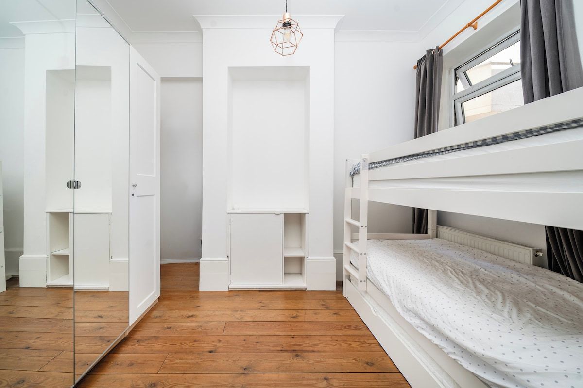 Een slaapkamer met een stapelbed, een kledingkast en een deur naar een andere kamer.