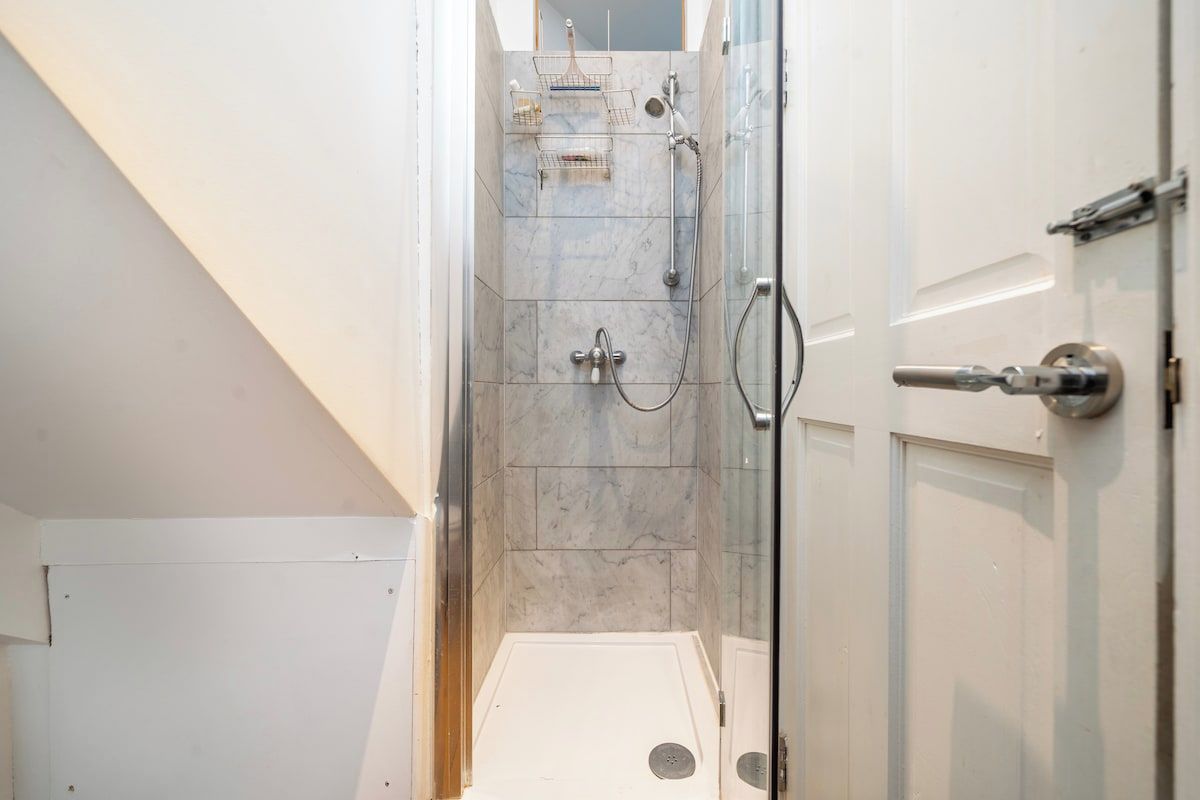 Eine Dusche mit Glastür, Handtuchhalter und Duschkopf.