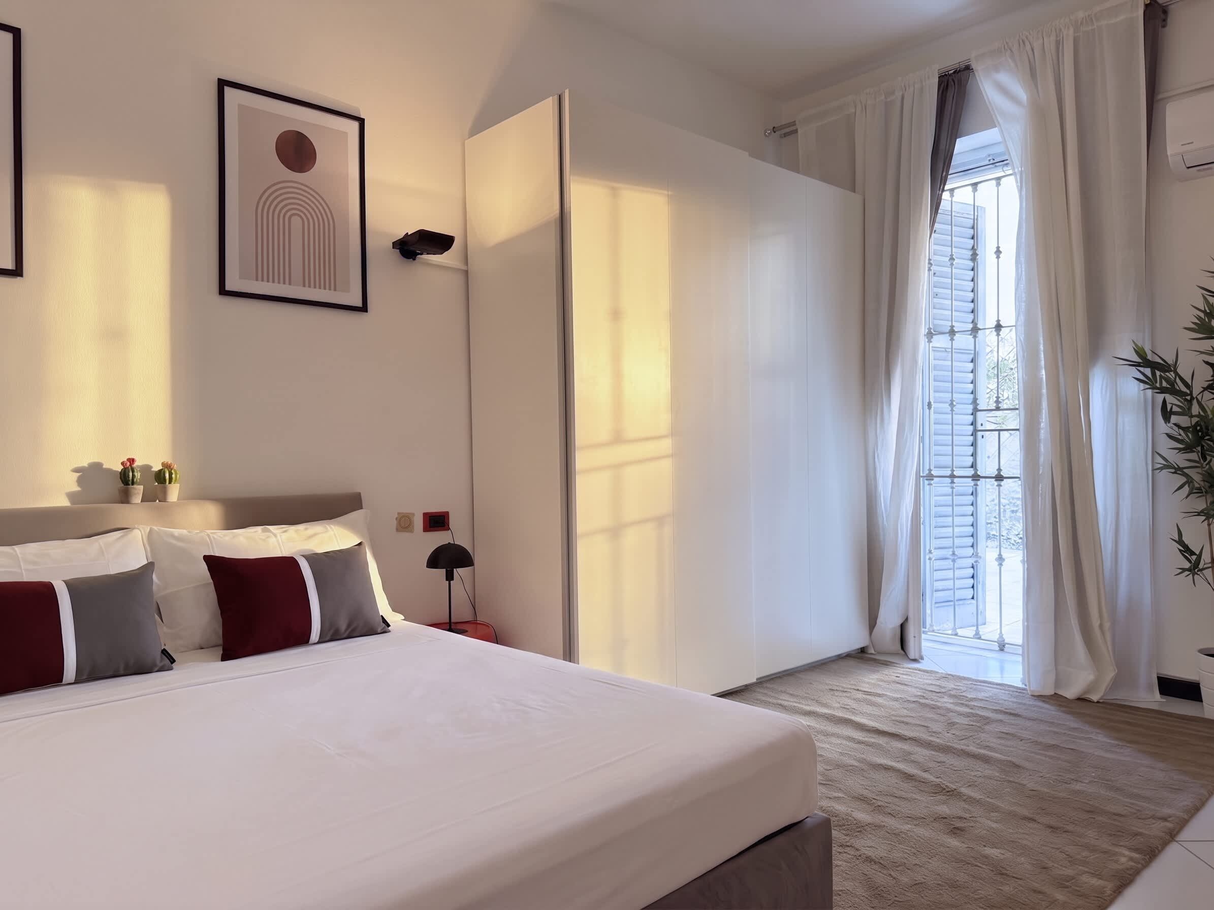 A hotel room with a large bed, a bedside table, a lamp, and a window with curtains.