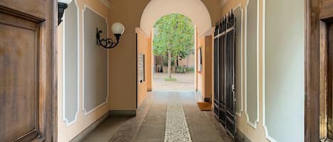 A hallway with a tiled floor, wooden doors, and a wall-mounted light fixture.