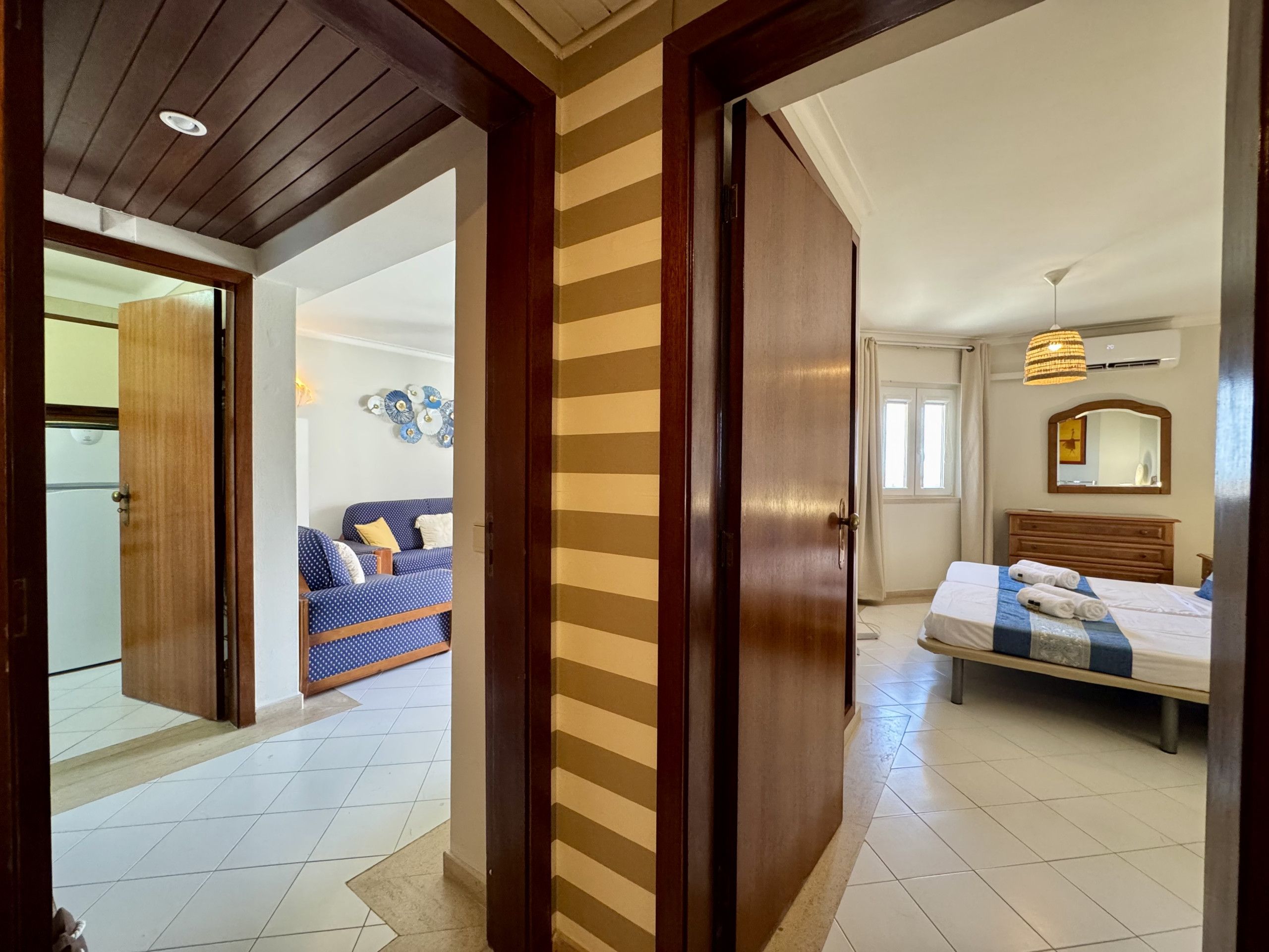 A hotel room with a bed, a bedside table, a mirror, and a window.