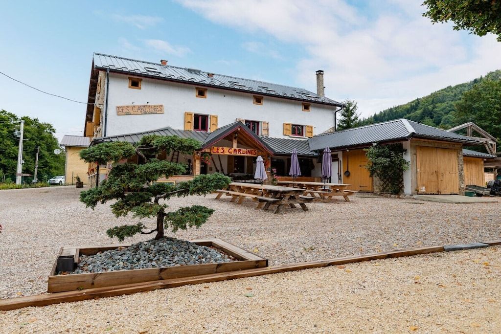 Een gebouw met een bord waarop 'LES CARINES' staat en een kleine tuin met een bonsai-boom.
