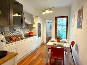 Una cocina moderna con armarios blancos, encimera de madera y comedor con una mesa lista para dos.