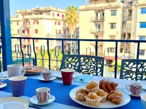 Un balcón con una mesa dispuesta para el desayuno, que incluye cruasanes, muffins y tazas.
