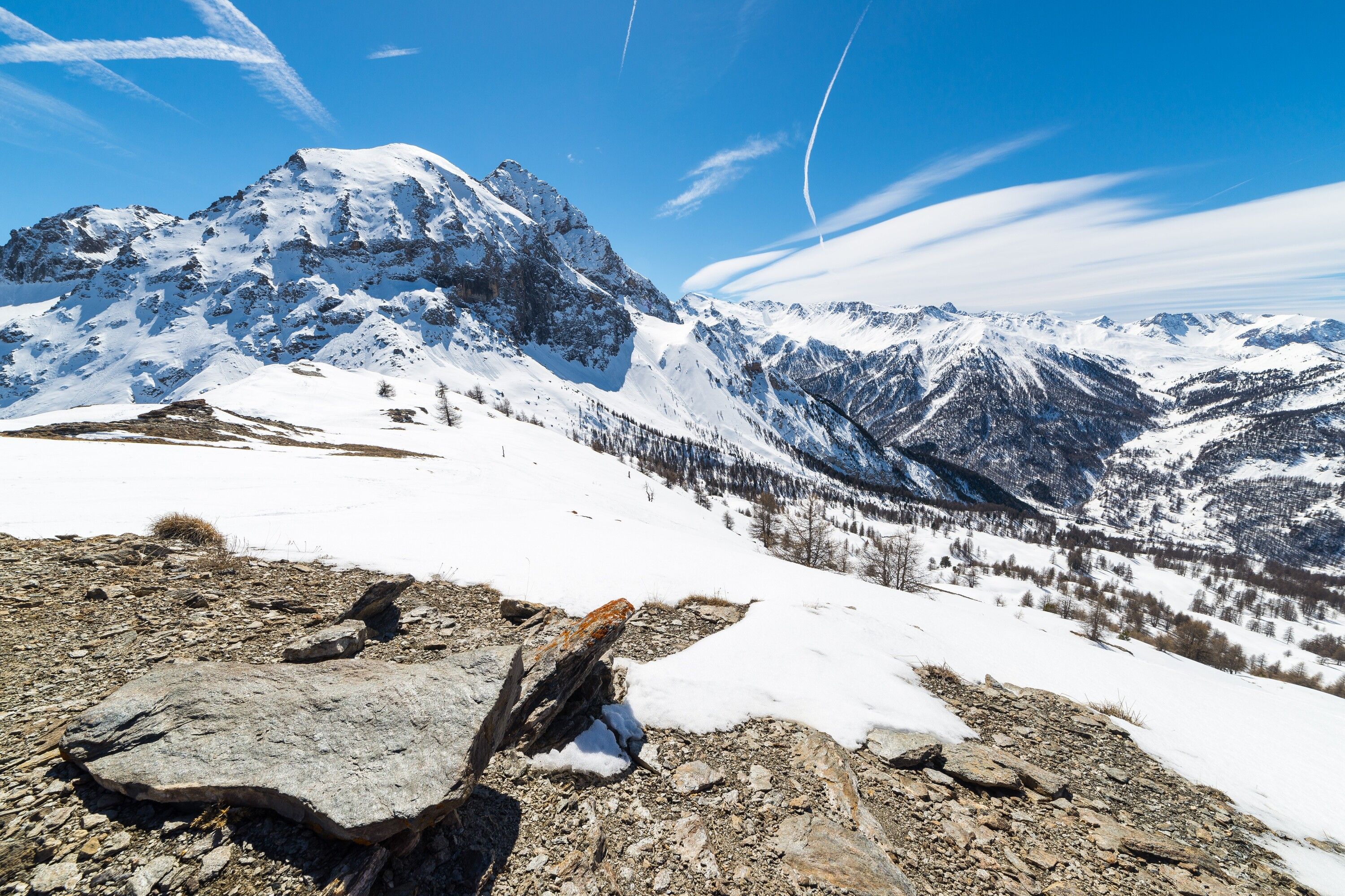 Un paysage montagneux enneigé, avec un terrain rocheux et un ciel dégagé.