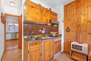 Una cocina con armarios de madera, un lavamanos de acero inoxidable y un microondas.