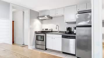 A modern kitchen with stainless steel appliances, white cabinetry, and a wooden floor.