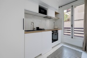 A modern kitchen with white cabinetry, a black microwave, and a built-in oven. - One-Bedroom Superior Apartment (Paris)
