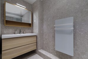 A bathroom with a mirror, sink, wooden vanity, and a towel rack. - One-Bedroom Superior Apartment (Paris)