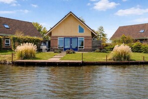 A two-story house with a large front door, a small porch, and a dock extending into a body of water. - Holiday home with 2 bedrooms (Medemblik)