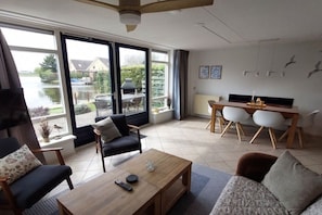 A spacious living area with a large sliding glass door leading to a patio, a dining table with chairs, and a sofa.