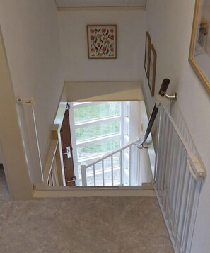 Eine Treppe mit Geländer, eine Tür zu einem Außenbereich und ein Heizkörper an der Wand.