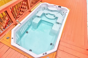 Ein Whirlpool auf einer Holzterrasse mit Metallgeländer.