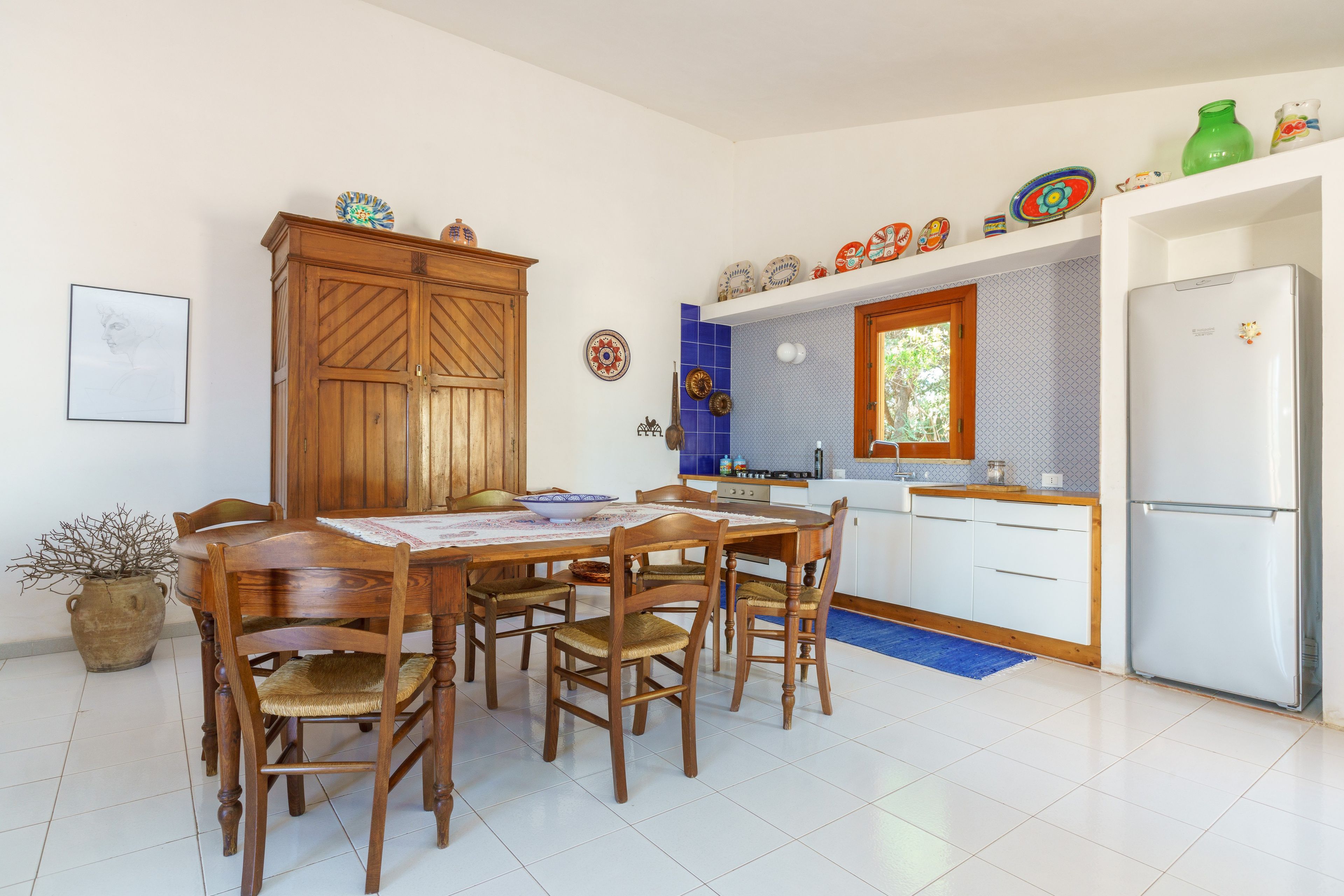 A kitchen with a dining table, chairs, a refrigerator, and various kitchen appliances.