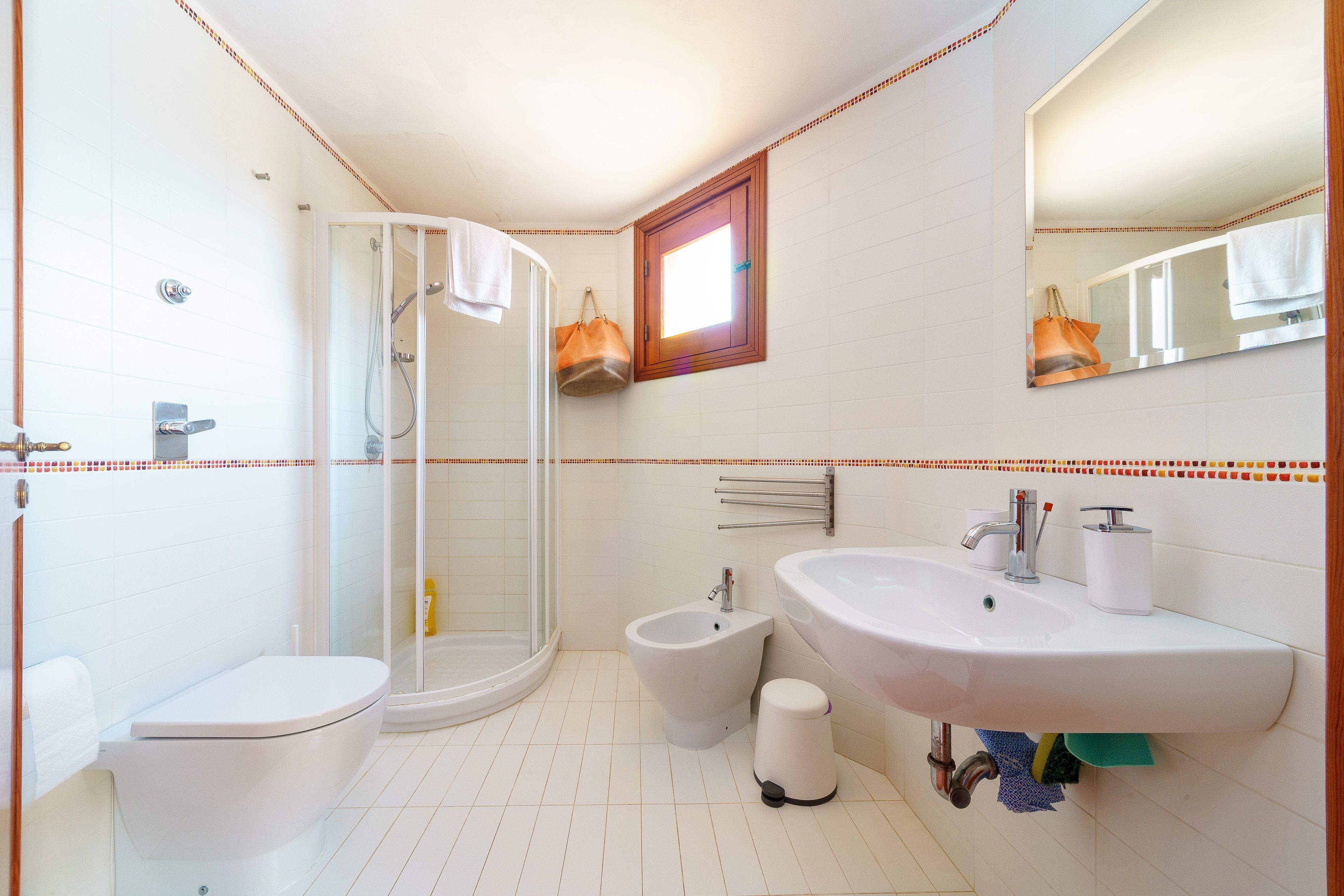 A bathroom with a toilet, bidet, sink, and a glass-enclosed shower.