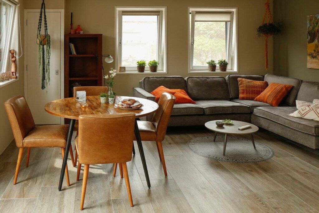 Ein modernes Wohnzimmer mit einem runden Esstisch, Ledersofas und einem Bücherregal.