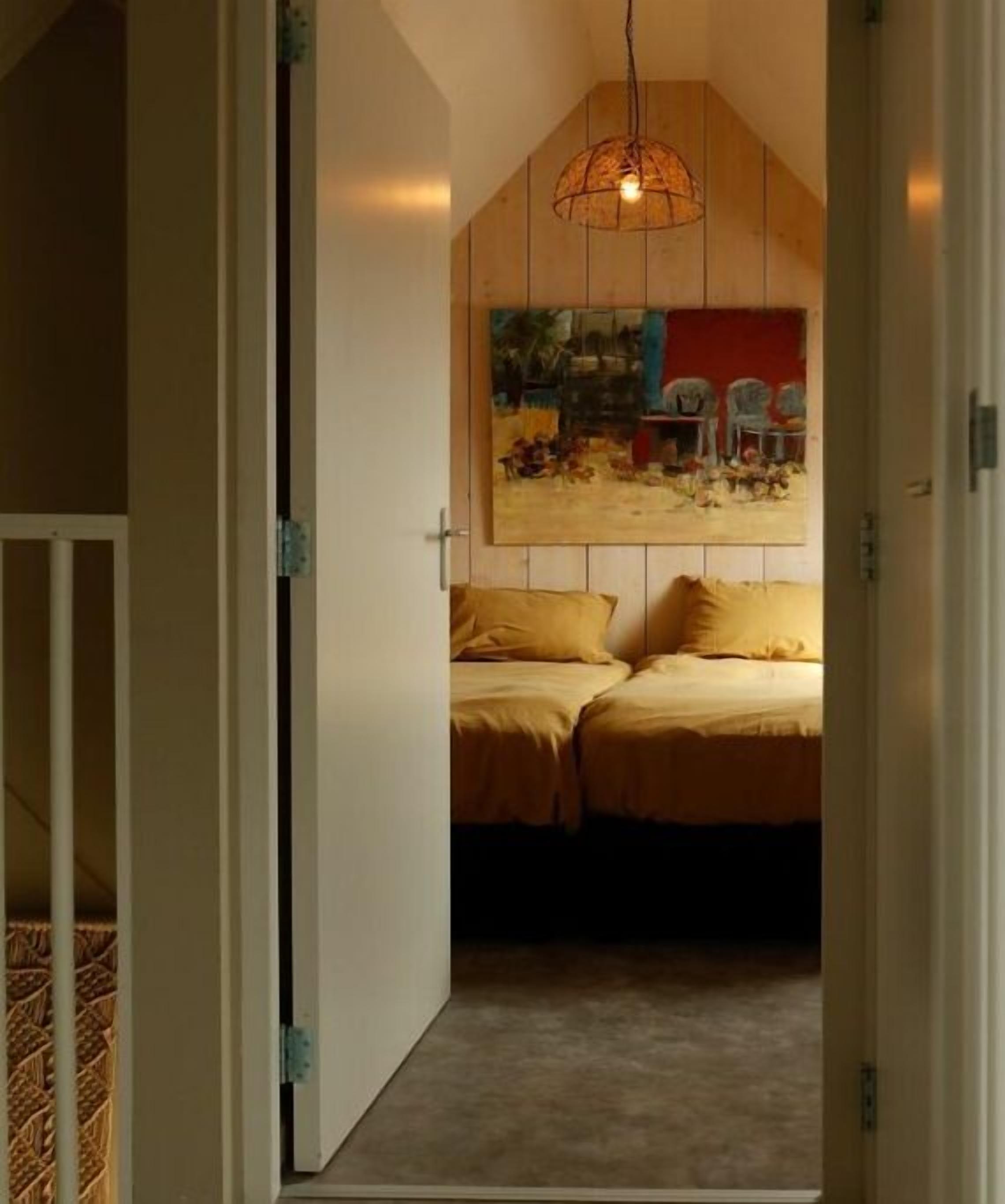 Une chambre à coucher avec un lit, un luminaire suspendu et un tableau au mur.