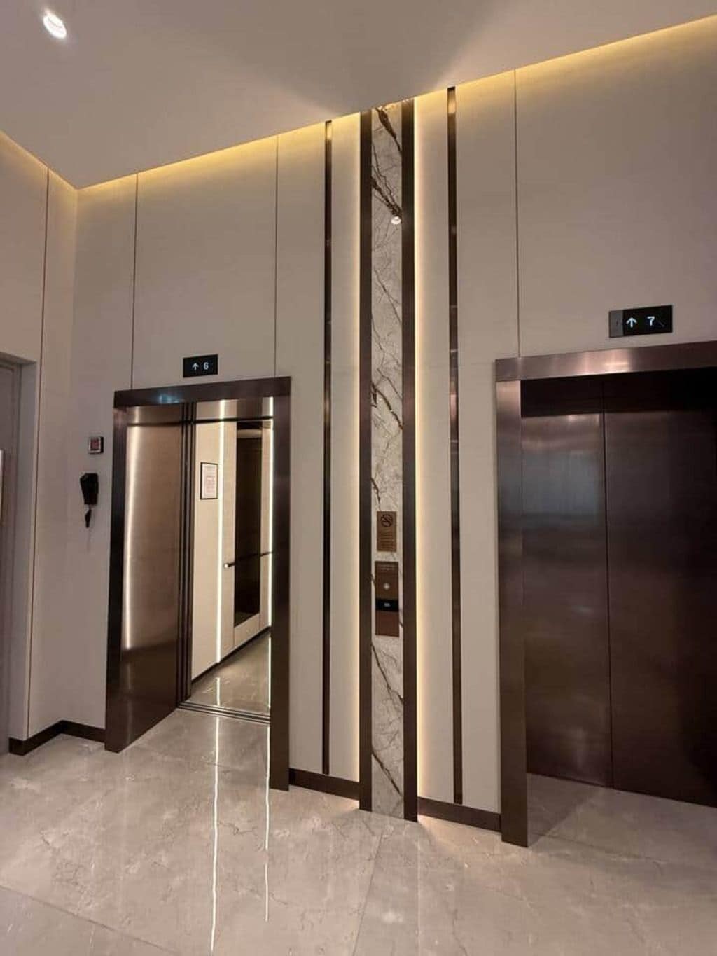 A modern elevator interior with a marble wall and a reflective floor.
