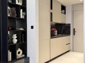 A modern kitchen with built-in cabinets, a black countertop, and a red appliance. - Central Studio at Hyde Walk   Rooftop Pool & Free Parking (Dubai)