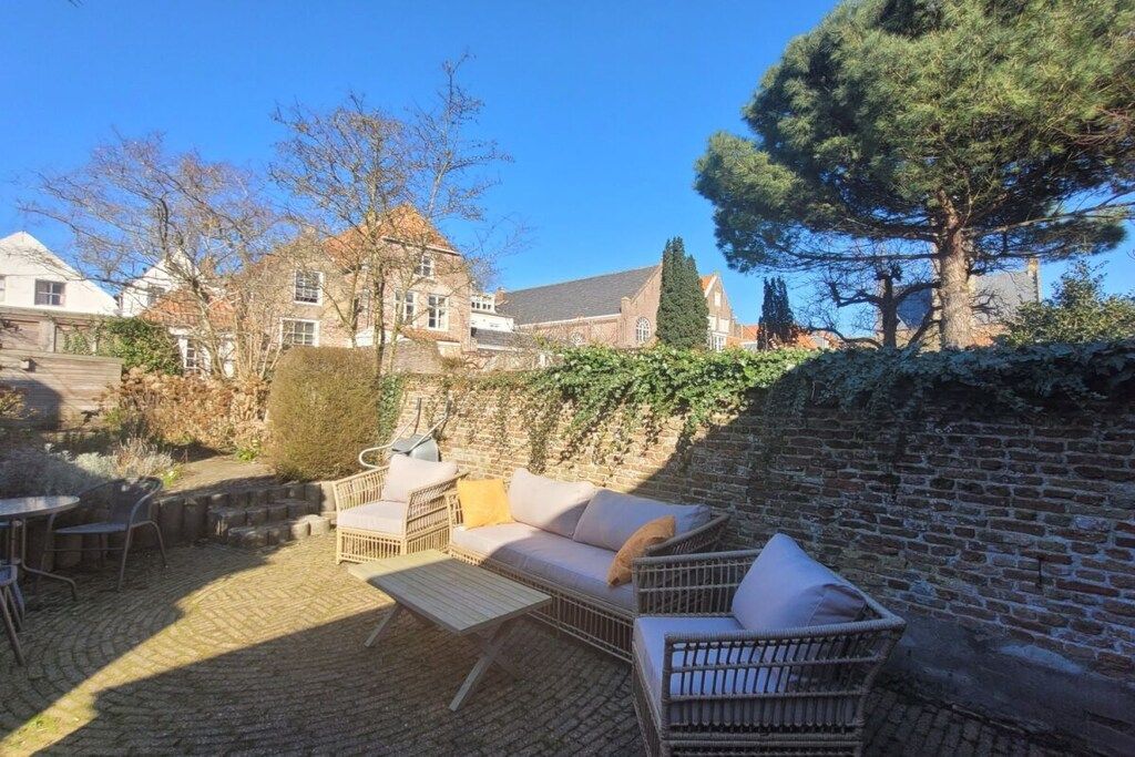 Ein Innenhof mit Gartenmöbeln, einer Backsteinmauer und einem großen Baum.