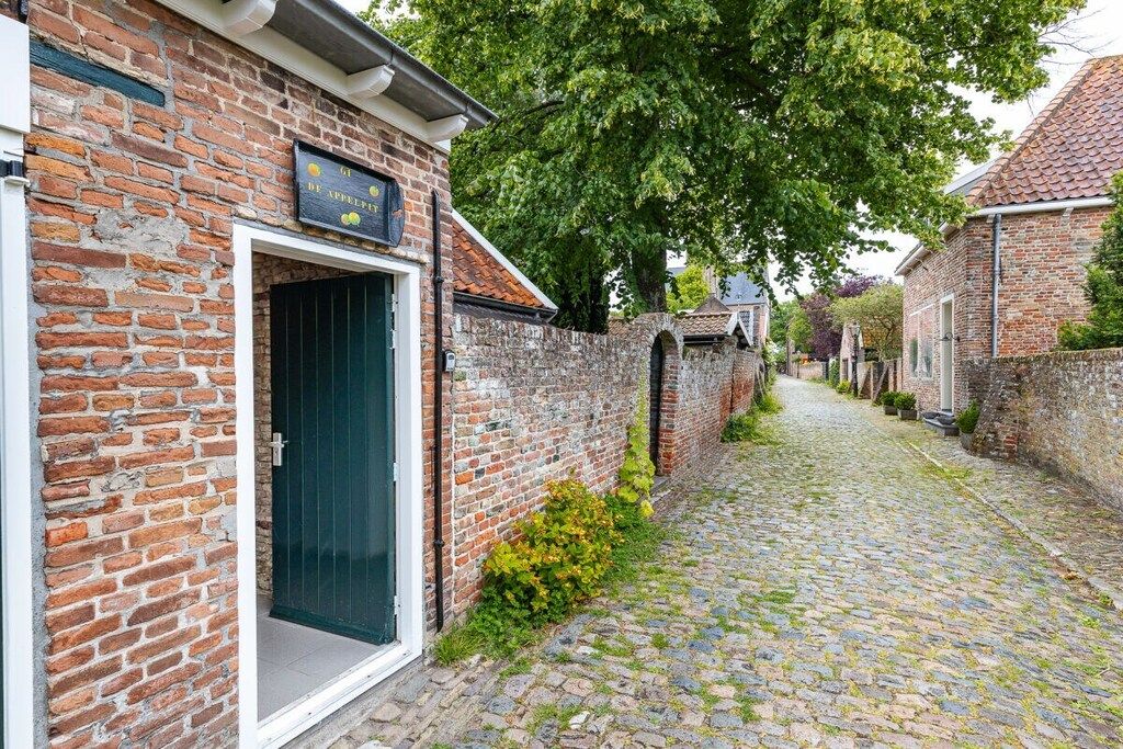 A cobblestone street with a brick building featuring a sign with fruit imagery.