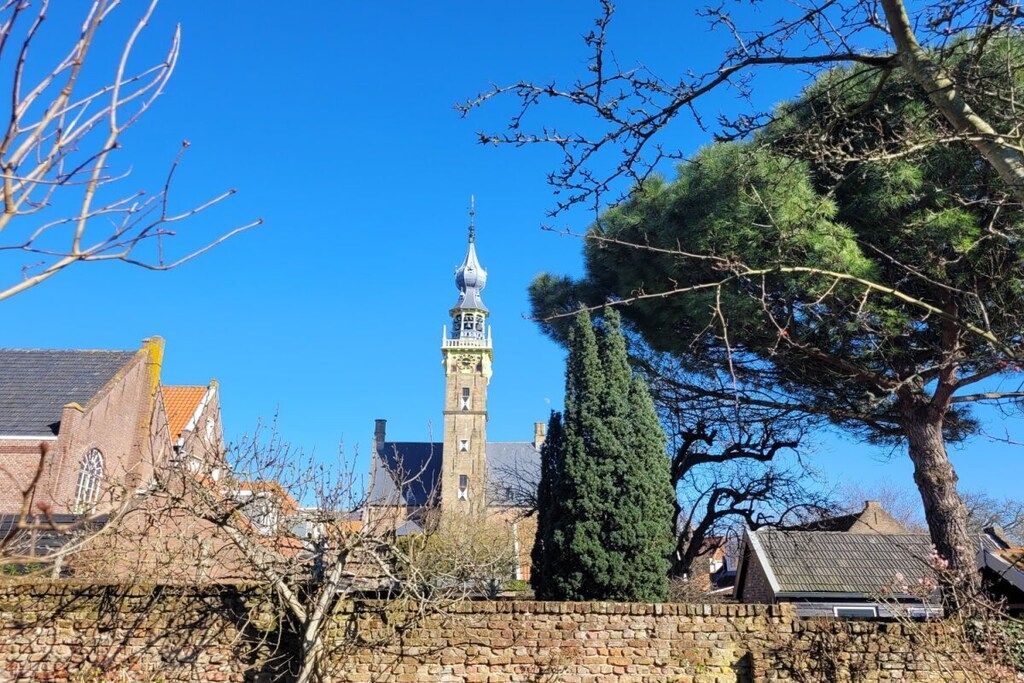Ein historisches Gebäude mit einem markanten Turm und einer Steinmauer im Vordergrund.