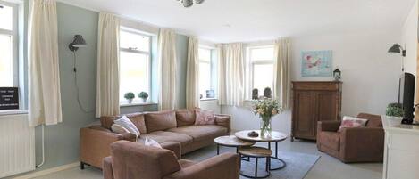 Ein Wohnzimmer mit einem braunen Sofa, einem runden Couchtisch und einem Schrank.