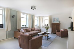A living room with a brown sofa, a round coffee table, and a cabinet. - Grijpskerkseweg 3 Front (Oostkapelle)