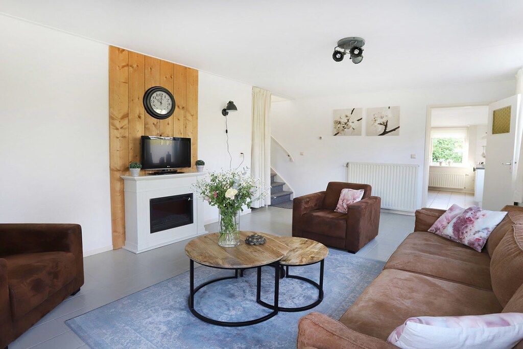 Ein Wohnzimmer mit braunem Sofa, einem Couchtisch, einem Fernseher und einem Kamin.