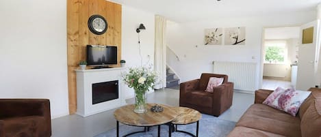 A living room with a brown sofa, a coffee table, a television, and a fireplace.