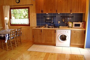 Une cuisine compacte avec des meubles en bois, un lave-linge et un coin repas comprenant une table et des chaises.