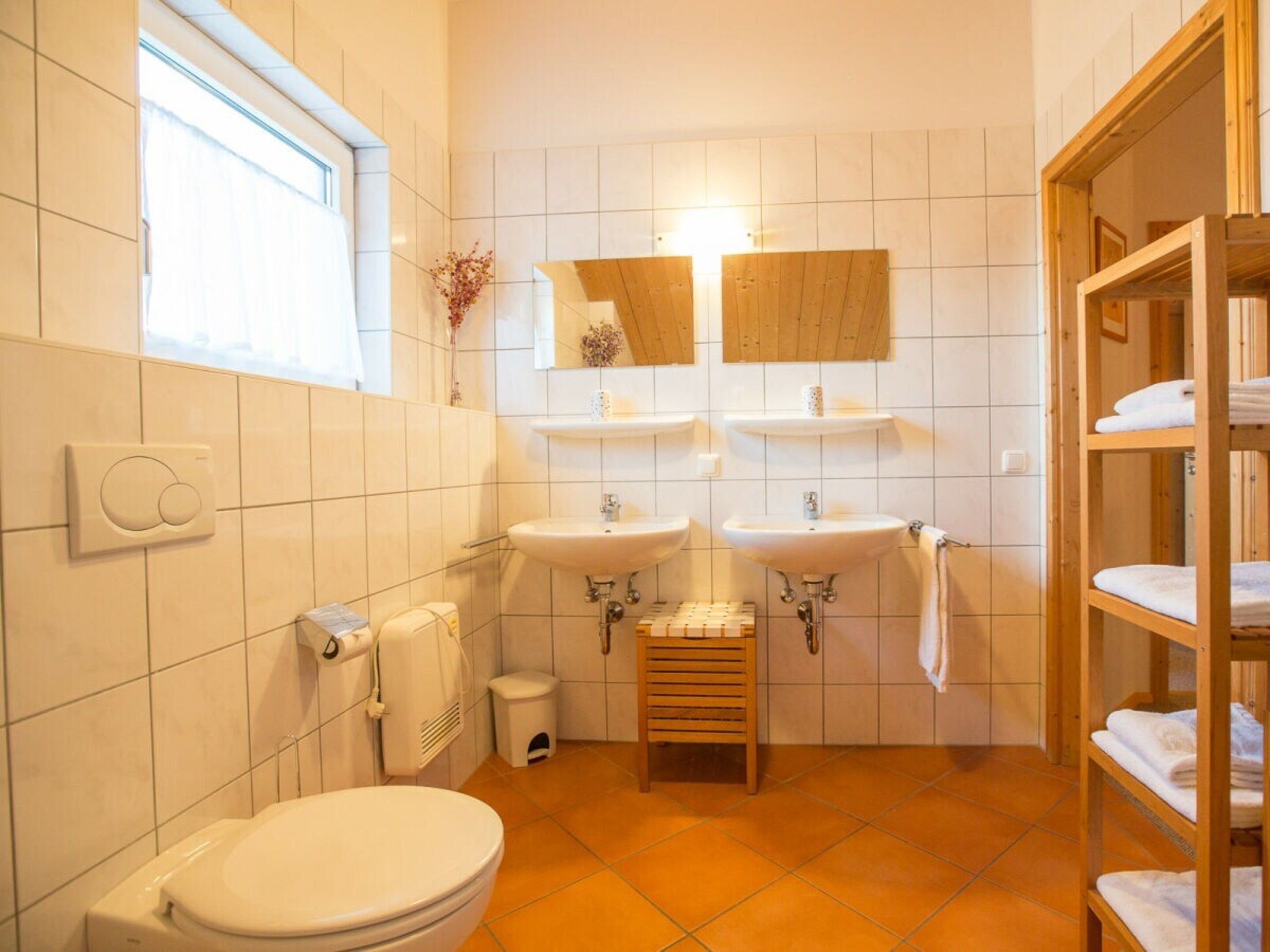 Une salle de bain comprenant des toilettes, deux lavabos, un miroir et un porte-serviettes.