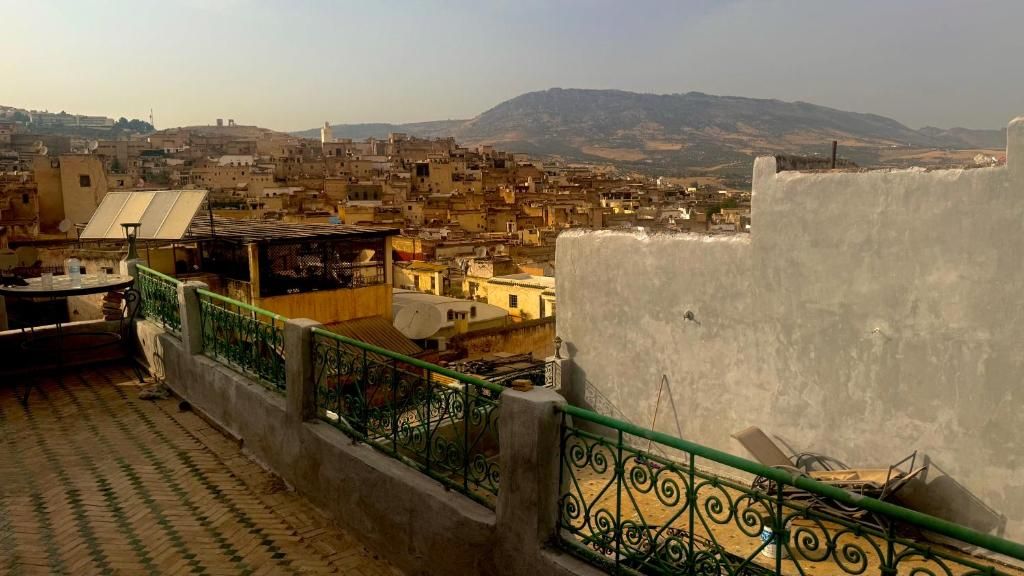 A rooftop terrace with a view of a densely packed cityscape and distant hills.