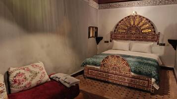 Una habitación con una cama que incluye un cabecero ornamentado, un sofá rojo y una alfombra estampada.